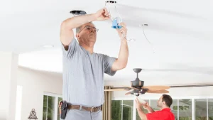 Electrician installing or wiring a ceiling fan in a residential home
